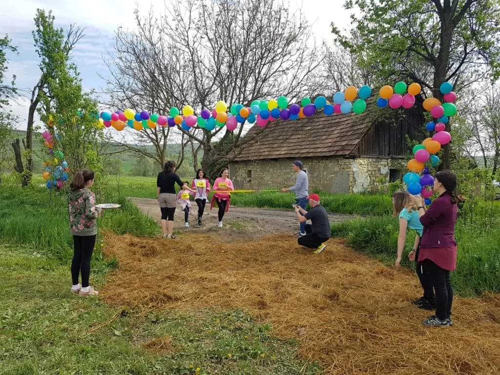 Participanții la cros trec pe sub o arcadă de baloane colorate